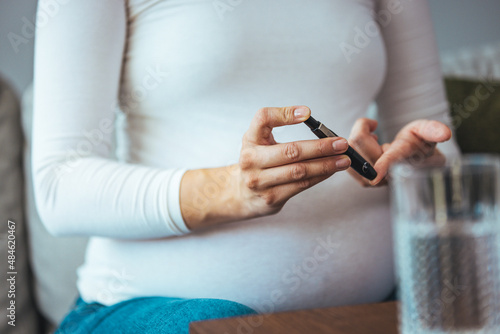 A pregnant woman hands using lancet on finger to check blood sugar test level by Glucose meter, Healthcare Medical and Check up, Medicine, diabetes, glycemia, health care and people concept