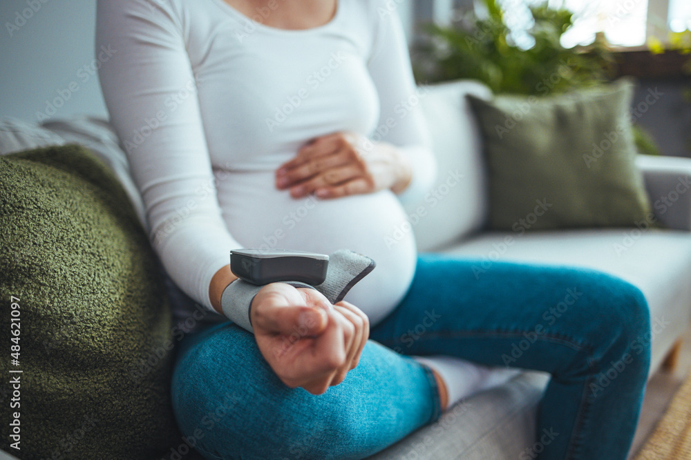 Pregnant woman measuring blood pressure, health check of expecting mom. She checking blood pressure at home. High pressure problem during pregnancy concept. Pregnant woman measuring blood pressure, health check of expecting mom. She checking blood pressure at home. High pressure problem during pregnancy concept.