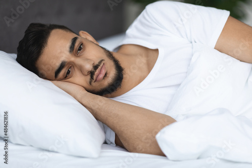 Sleep Disorders. Upset Arab Man Lying In Bed With Open Eyes. Closeup