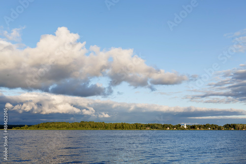 Scenic view on the calm Volga river with forest on horizon. Fluffy clouds reflected in mirrorlike glossy water. Summer, Volga, Tver region, Russia © Elena