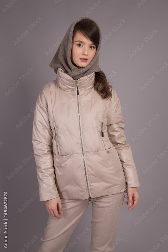 A young girl model posing at the camera demonstrates clothes in different positions.Shooting in a clothes studio on a gray background showing a model. A young girl model posing at the camera demonstrates clothes in different positions.Shooting in a clothes studio on a gray background showing a model.