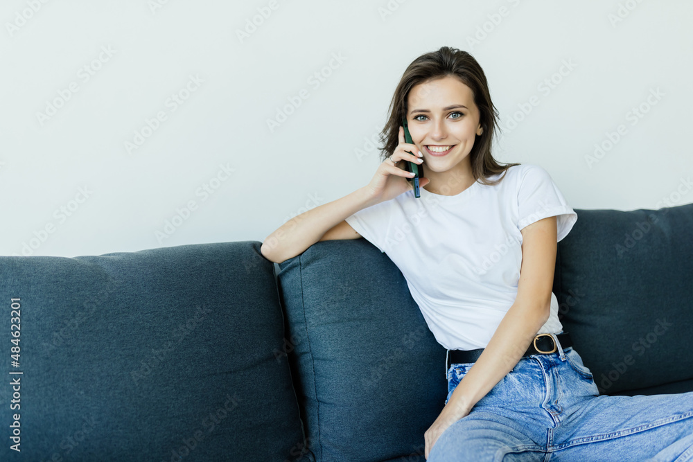 Happy young woman caller talking on the phone at home