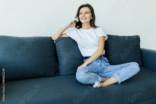 Young female using white mobile phone at home smiling