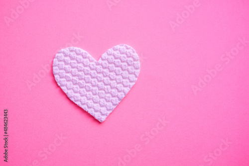 White fabric heart on pink table. Copy space on the right. Art love card.