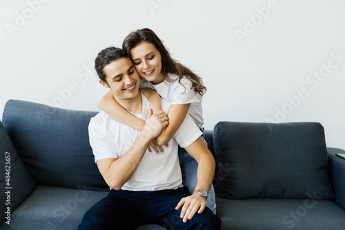 Cheerful couple smiling and hugging while sitting on sofa at home © F8  \ Suport Ukraine