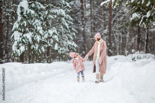 mom and daughter play in the winter forest