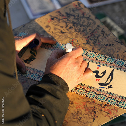 Arabic calligraphy manuscript. Writer writing by hand in the street photo