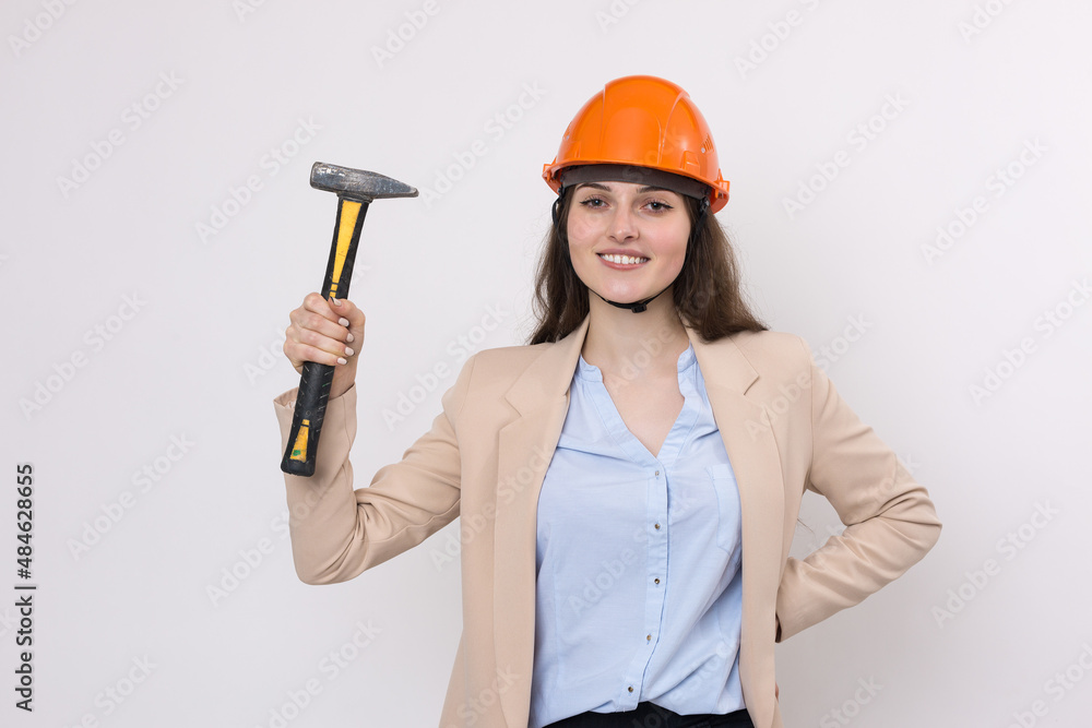 Girl engineer in an orange construction helmet with a hammer on a white background. Girl engineer in an orange construction helmet with a hammer on a white background.