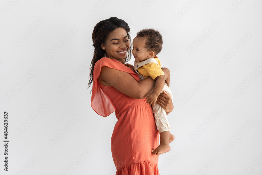 Motherhood Concept. Portrait Of Young Black Mom With Infant Son On Arms