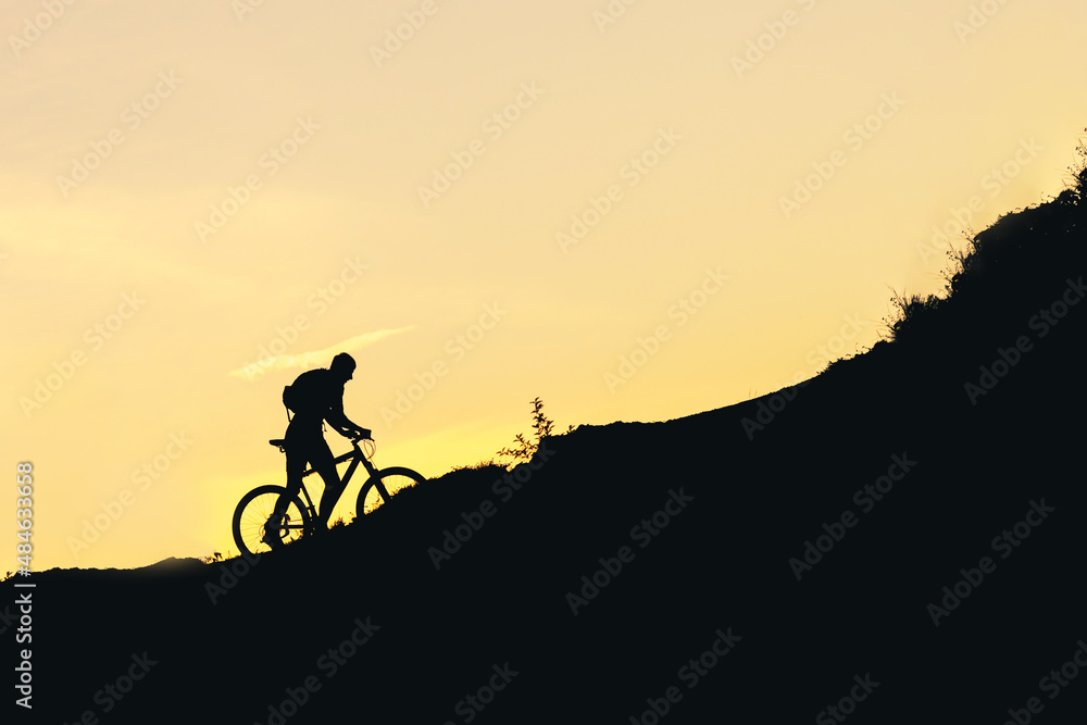 silhouette of a man on a bicycle going uphill during sunset silhouette of a man on a bicycle going uphill during sunset
