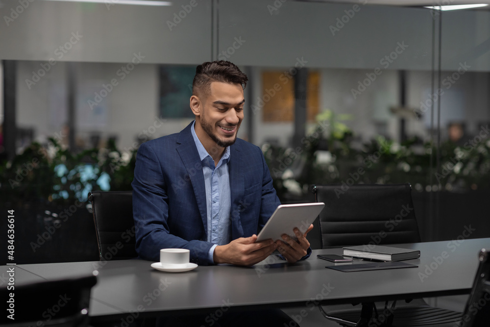 Smiling handsome middle eastern entrepreneur using digital tablet