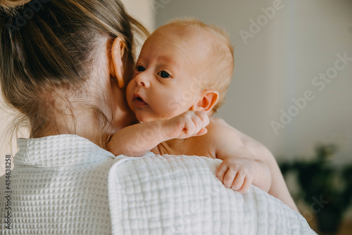 Fotografie Mother holding newborn baby on shoulder, with a burping cloth.