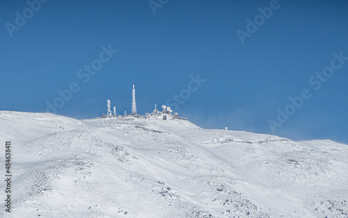 A distant mountain with a military base on it, in the snow © or