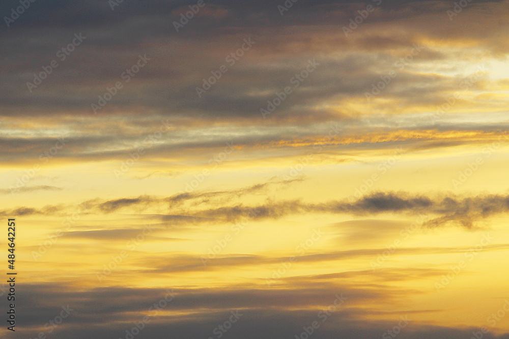 Sun below the horizon and clouds in the fiery dramatic orange sky at sunset or dawn backlit by the sun. Place for text and design, wallpaper and background