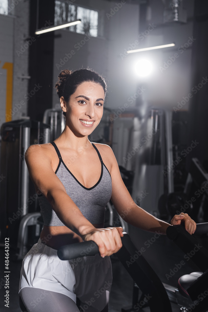 Middle east sportswoman training on elliptical trainer and smiling at camera in gym. Middle east sportswoman training on elliptical trainer and smiling at camera in gym.