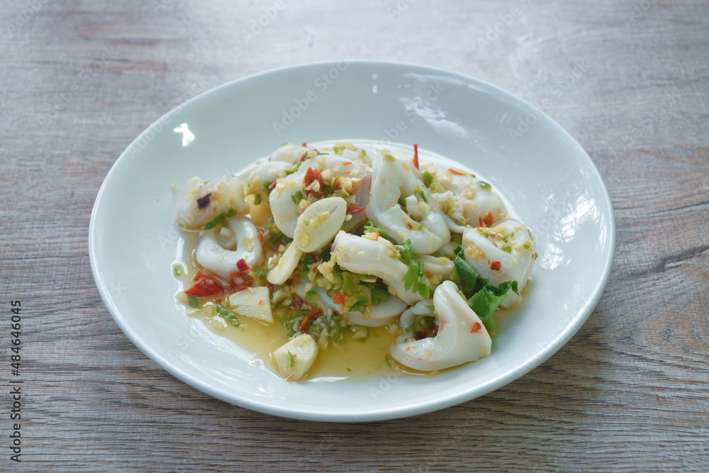 Thai spicy and sour steamed slice squid salad in lemon sauce on plate Thai spicy and sour steamed slice squid salad in lemon sauce on plate