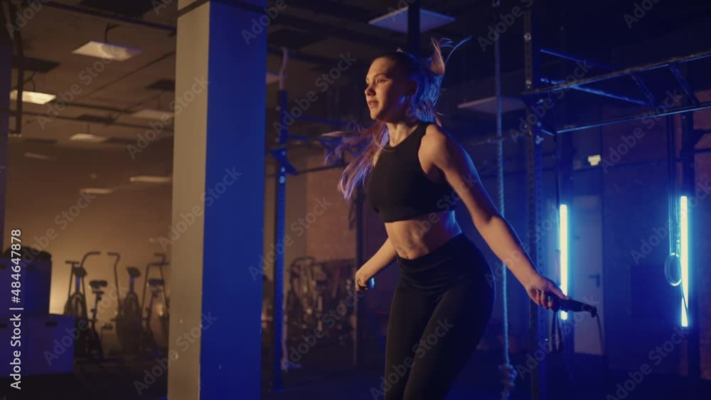 Slow motion: Young woman skipping rope. woman jump roping in the gym as part of her workout routine, determined woman focused