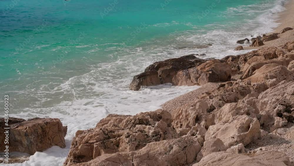 Rocky sea beach with clear azure water. Waves break on pink rocks. Pebble beach in Kas, Turkey. Rocky sea beach with clear azure water. Waves break on pink rocks. Pebble beach in Kas, Turkey.