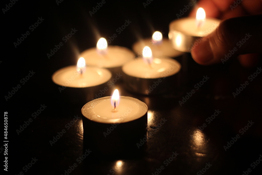 Man's hand lighting several candles on a wooden table Man's hand lighting several candles on a wooden table