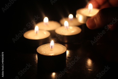 Man's hand lighting several candles on a wooden table