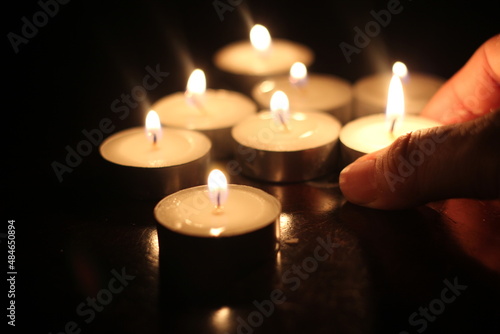 Man s hand lighting several candles on a wooden table