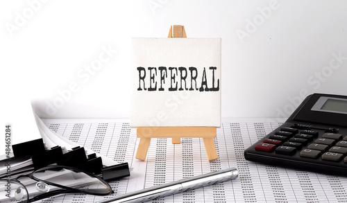 text REFERRAL on easel with office tools and paper.Top view. Business concept photo