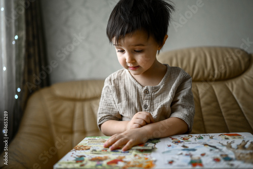 a little boy is sitting on the couch at home and looking at pictures in a book