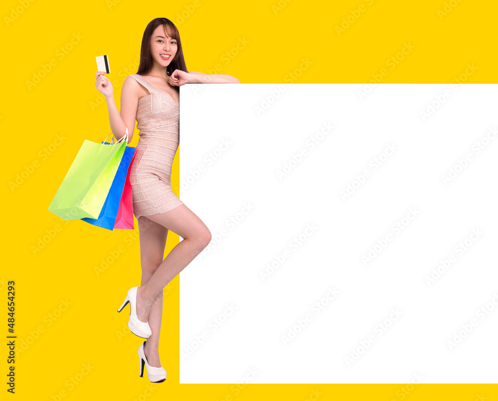 Young woman holding blank billboard sign and shopping bags Young woman holding blank billboard sign and shopping bags