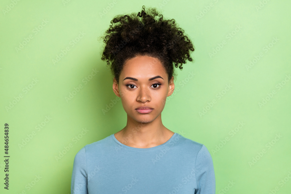 Photo of serious confident young curly lady dressed blue shirt isolated green color background Photo of serious confident young curly lady dressed blue shirt isolated green color background