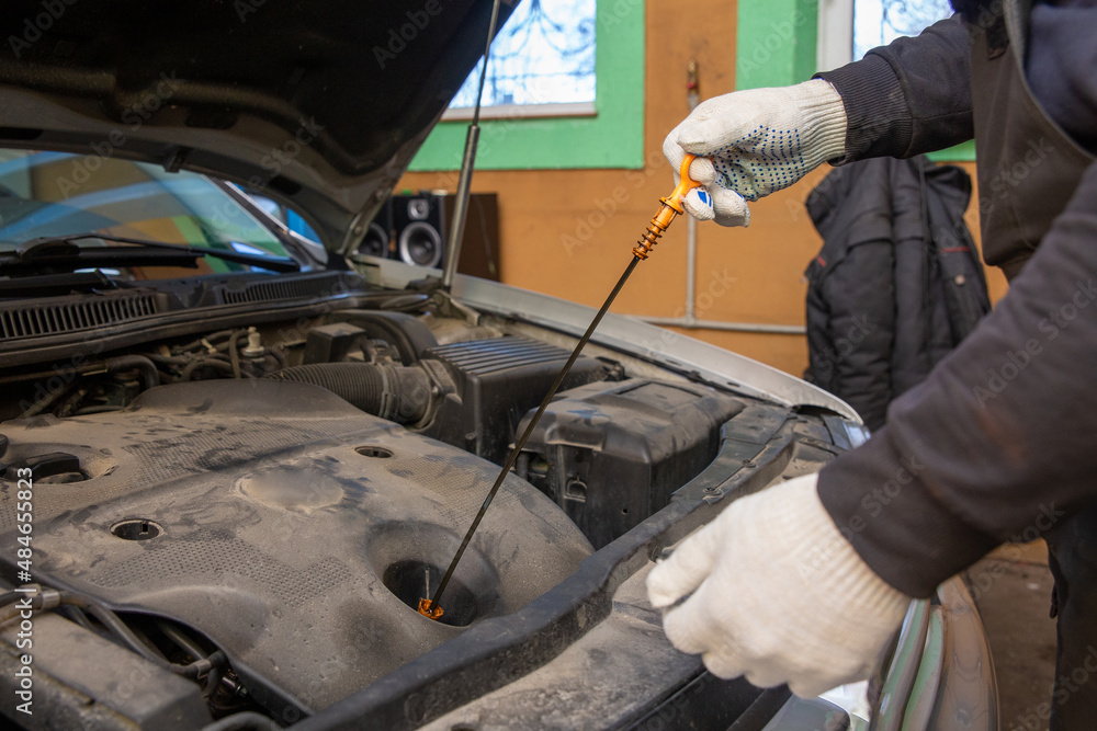 Car mechanic checking oil level in a mechanical workshop. Car mechanic checking oil level in a mechanical workshop.