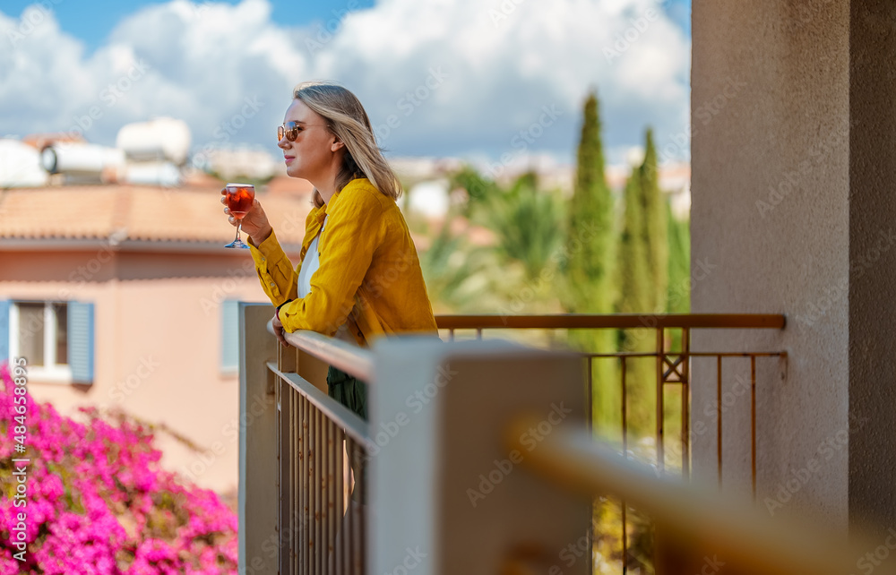 Woman with red wine enjoys her vacations on the balcony.