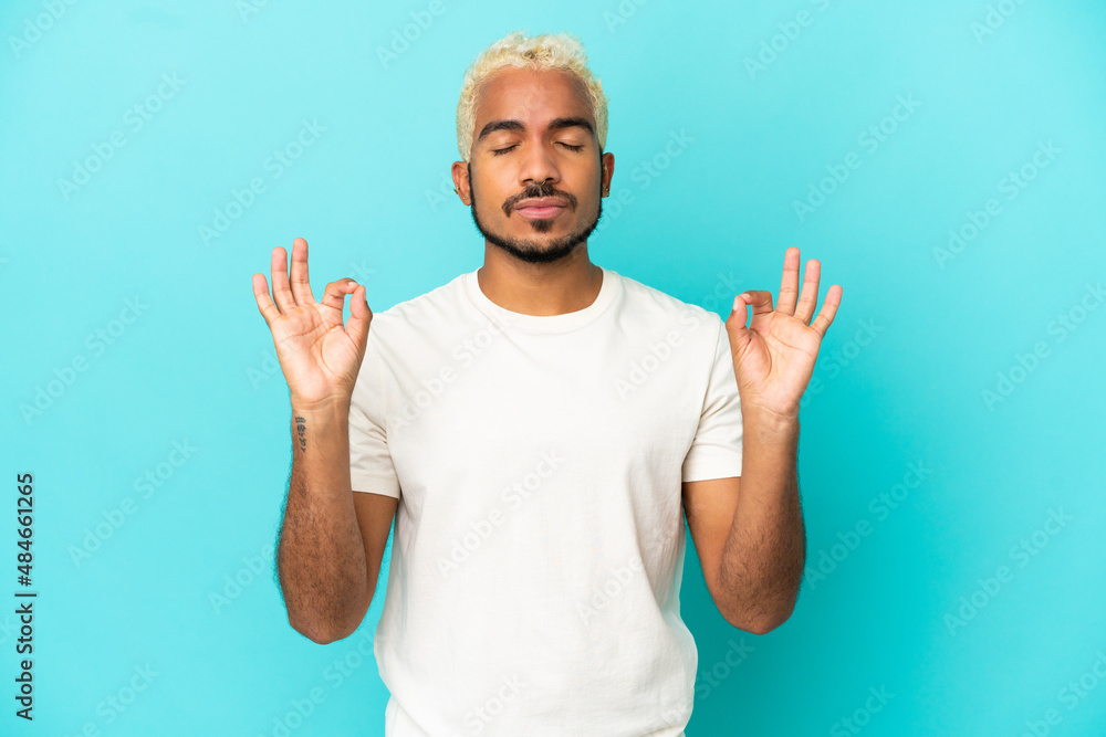 Young Colombian handsome man isolated on blue background in zen pose Young Colombian handsome man isolated on blue background in zen pose
