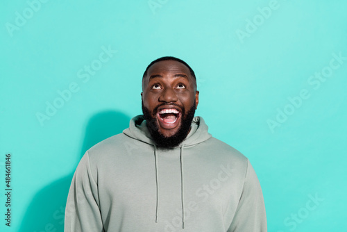 Portrait of attractive cheerful guy looking up guess copy space new isolated over bright teal turquoise color background