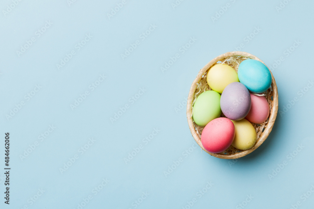 Multi colors Easter eggs in the woven basket on colored background . Pastel color Easter eggs. holiday concept with copy space Multi colors Easter eggs in the woven basket on colored background . Pastel color Easter eggs. holiday concept with copy space