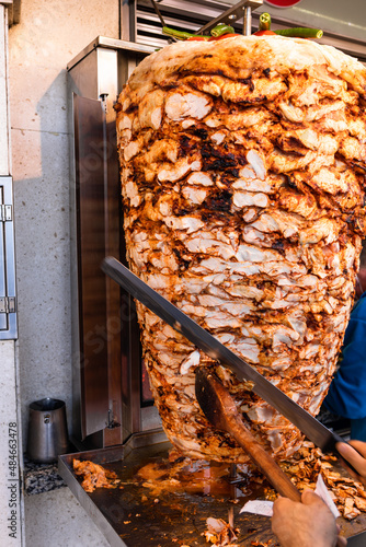 Chef cutting grilled chicken meat from rotating spit making traditional turkish street food Doner Kebab (Shawarma or Gyros in other cultures) in Istanbul, Turkey photo