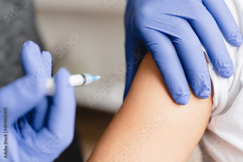 Closeup cropped image of patient s forearm and doctor nurse making injection  vaccine against Covid19 coronavirus. Vaccinated with syringe