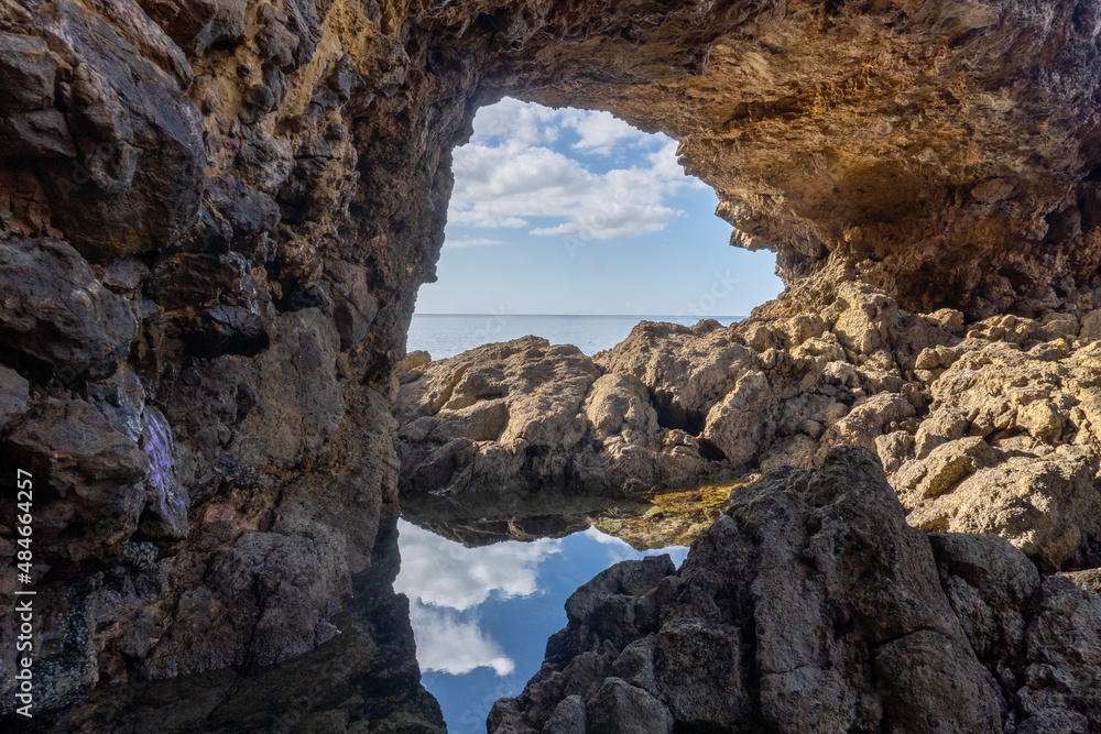Window's nature, from a hole in the rocks you can see the sea and the reflection of the sky in a puddle 
