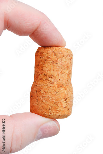The champagne cork is held in the fingers of a person. On a white background, close-up