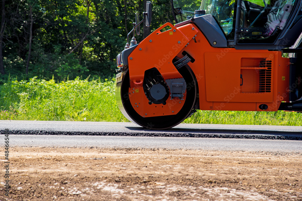 industrial landscape with rollers that rolls a new asphalt in the roadway. Repair, complicated transport movement.