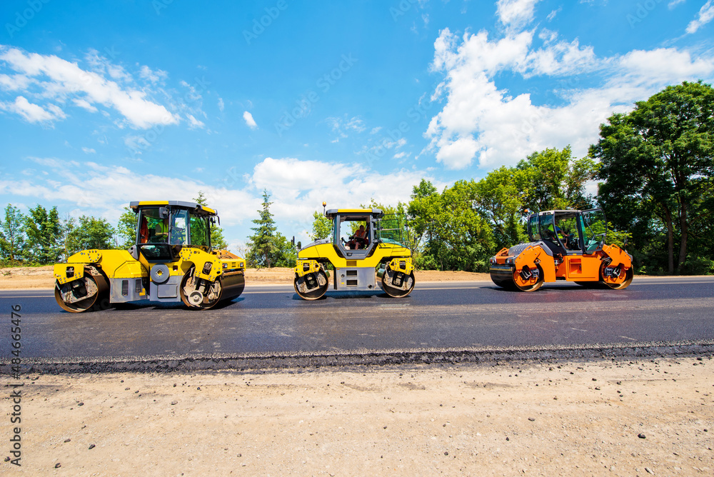 industrial landscape with rollers that rolls a new asphalt in the roadway. Repair, complicated transport movement.