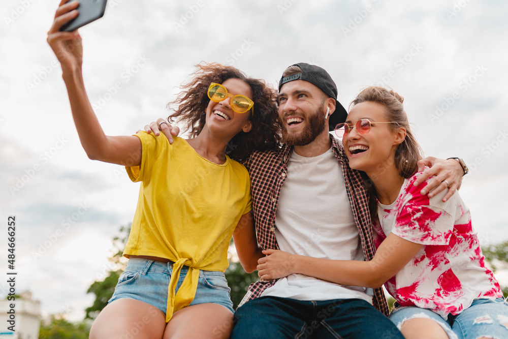 happy young company of smiling friends sitting in park happy young company of smiling friends sitting in park