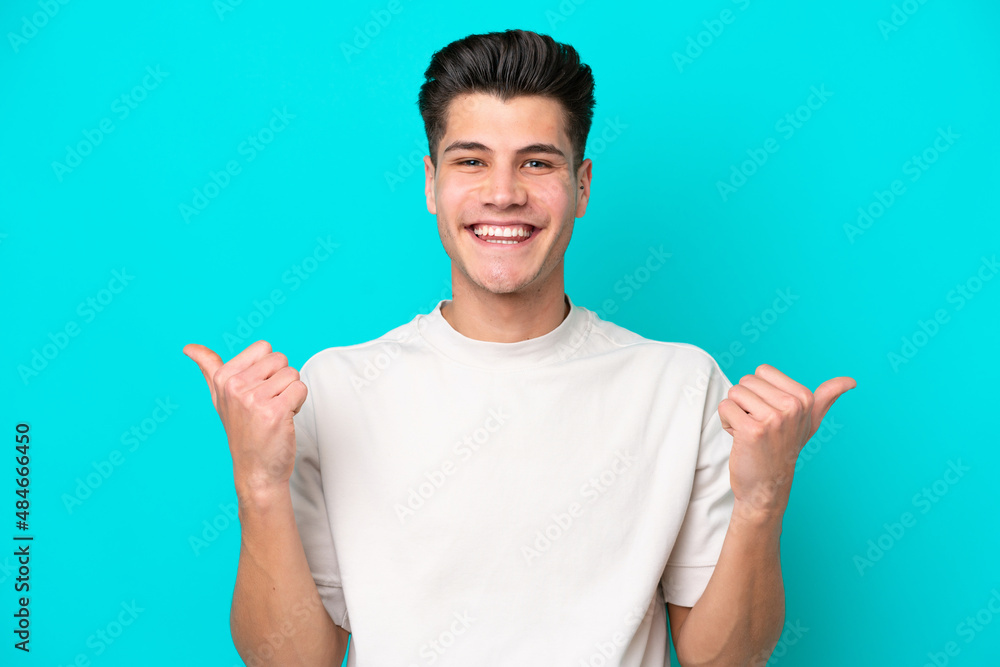 Young handsome caucasian man isolated on blue bakcground with thumbs up gesture and smiling