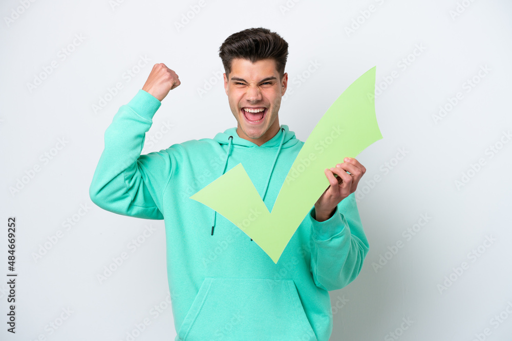 Young handsome caucasian man isolated on white bakcground holding a check icon and celebrating a victory Young handsome caucasian man isolated on white bakcground holding a check icon and celebrating a victory