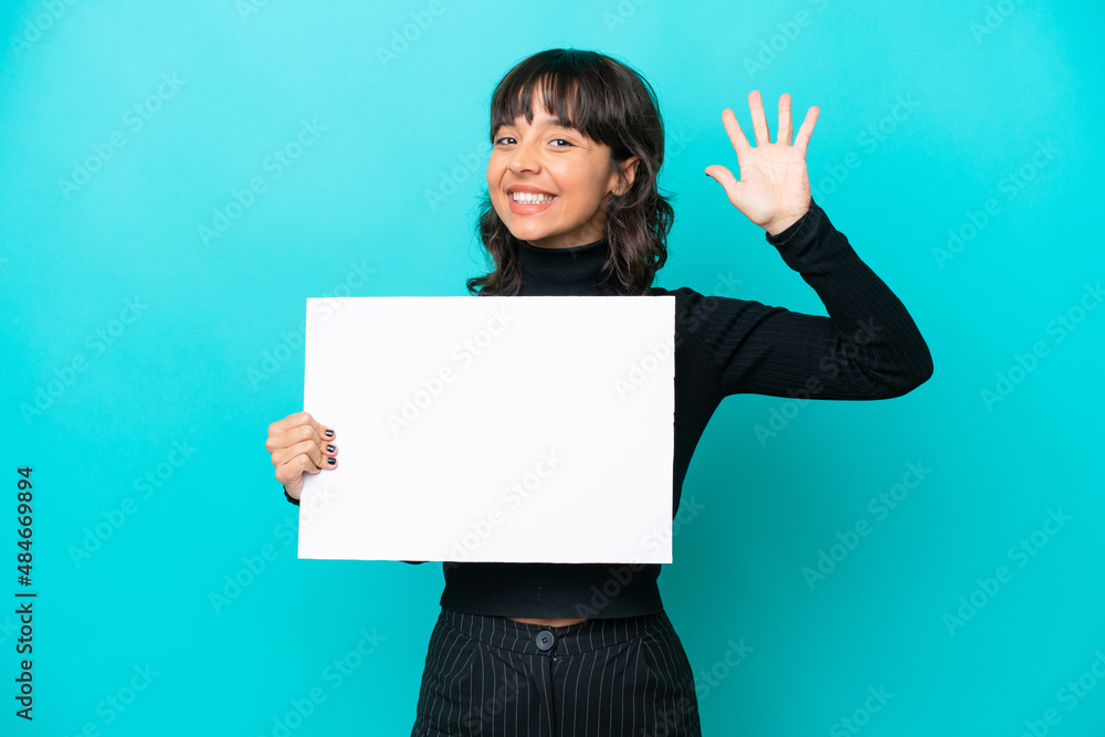 Young latin woman isolated on blue background holding an empty placard and saluting Young latin woman isolated on blue background holding an empty placard and saluting