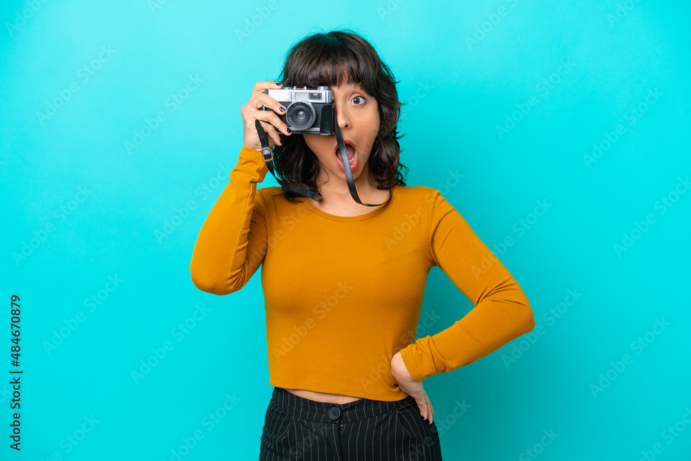 Young photographer latin woman isolated on blue background Young photographer latin woman isolated on blue background