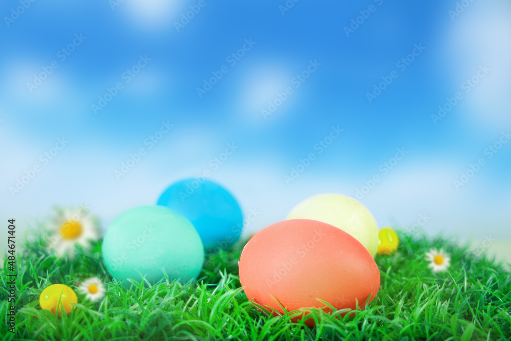 Colorful Easter eggs in the grass and blurred sky on the background.