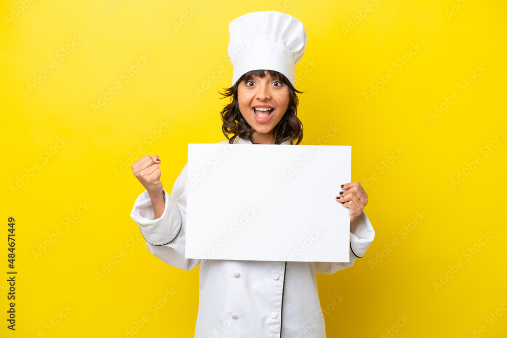 Young chef latin woman isolated on yellow background holding an empty placard and celebrating a victory Young chef latin woman isolated on yellow background holding an empty placard and celebrating a victory