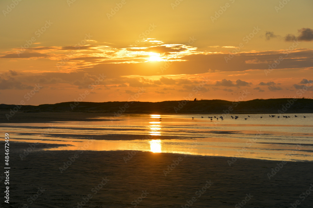 Sunset at low tide over the sea with sand beach