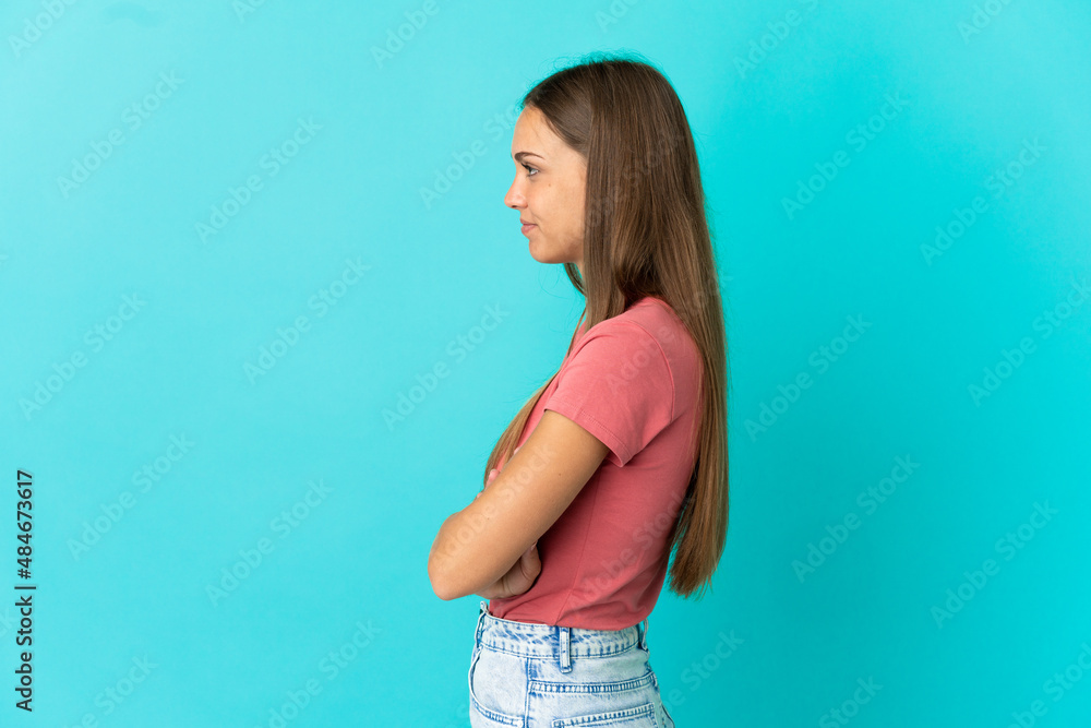 Young woman over isolated blue background in lateral position Young woman over isolated blue background in lateral position