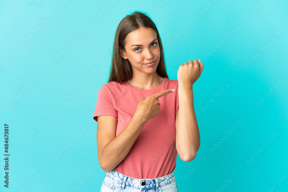 Fototapeta premium Young woman over isolated blue background making the gesture of being late